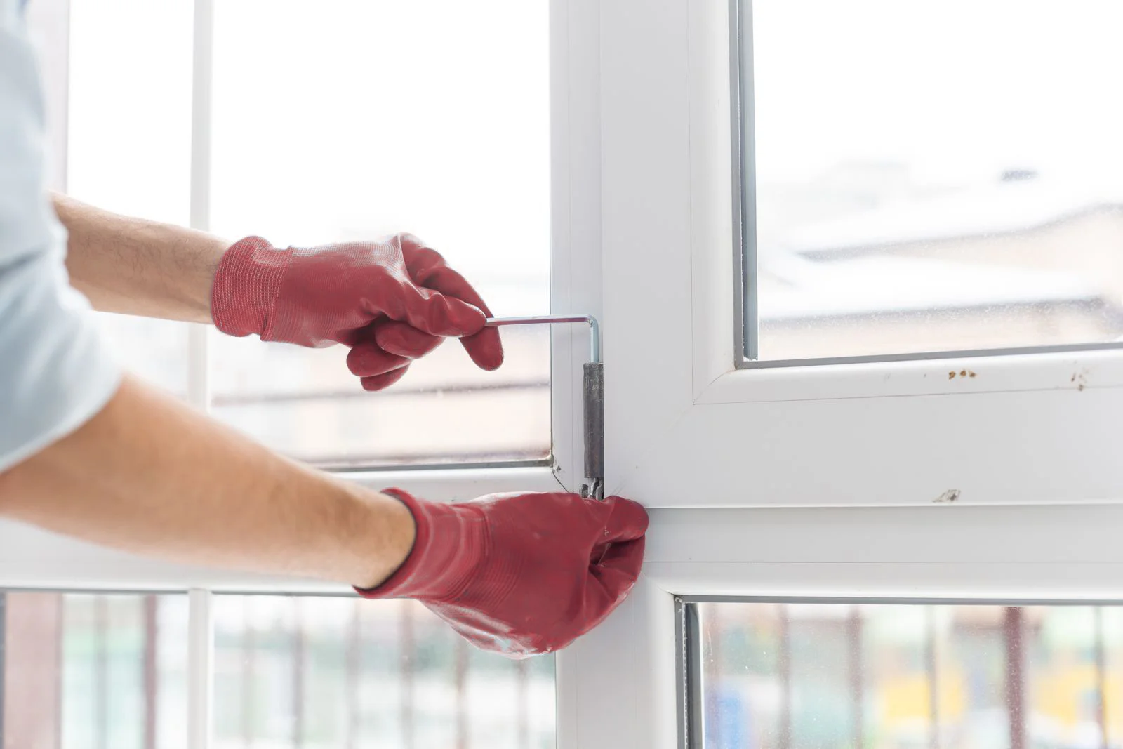 Professional technician adjusting window hinges with tools, close-up repair work